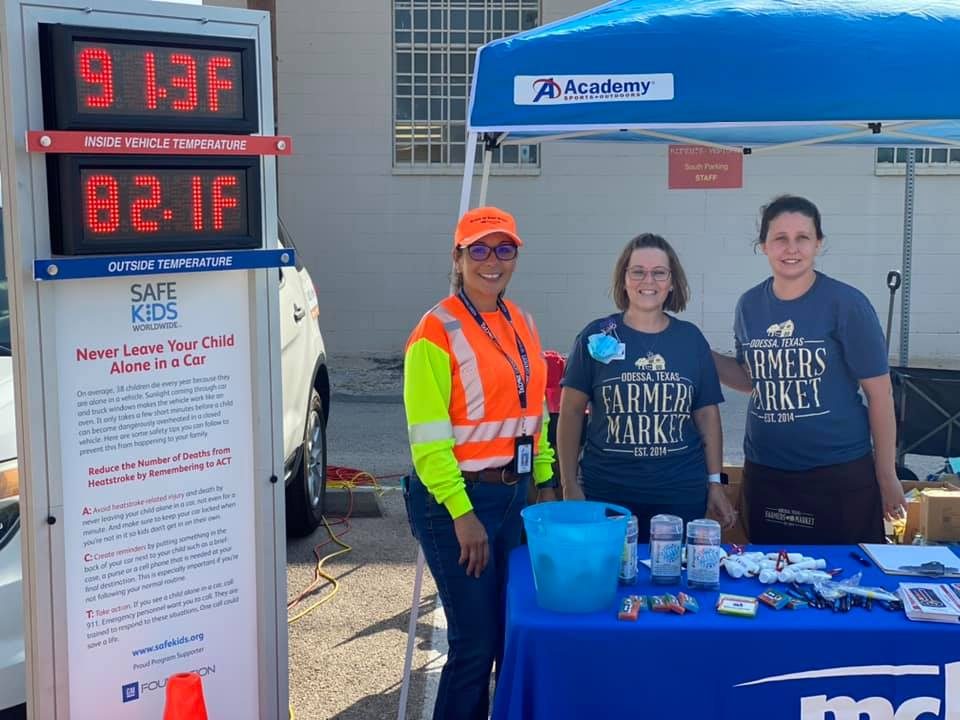 Medical Center Hospital staff at an injury prevention fair booth next to a heat warning sign